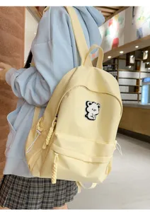 Cute canvas school backpack in light yellow with sweet bear patch for daily student use.