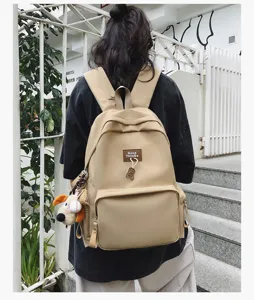 Detailed view of the casual beige campus backpack with cute bear pendant and spacious design.