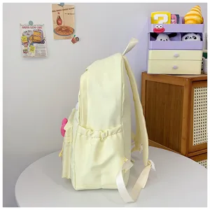 Side view of a cute light yellow canvas school backpack with side pockets and shoulder straps.