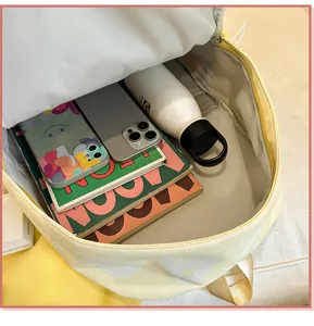 Detailed top view of a large canvas backpack interior filled with books, phone and water bottle.