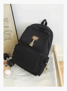 Black campus backpack detail showcasing durable fabric, front pocket, and bear charm.