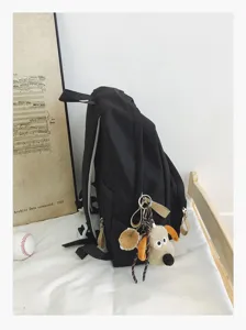 Minimalist black canvas backpack with cute puppy plush keychain for students and teens.
