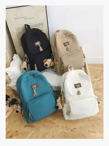 Detail shot showcasing four colorful student backpacks with cute plush dog pendants and woven labels.