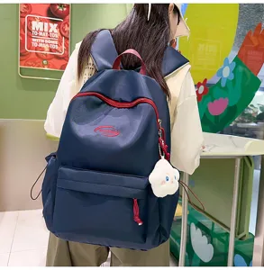 Vista detallada de una elegante mochila azul marino con detalles rojos y colgante de nube.