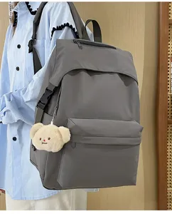 Detail view of casual grey nylon backpack featuring front zipper pocket and cute plush bear.