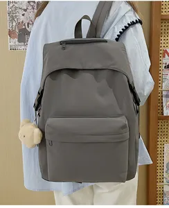 Grey nylon backpack detail, casual daily school bookbag with cute plush bear pendant accessory.