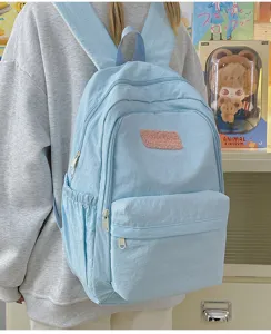 Light blue casual backpack for daily use, simple and fresh design with front pocket and plush patch details.