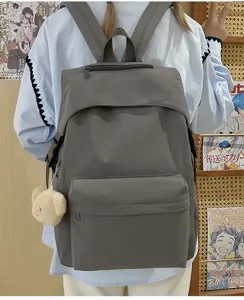 Detail view of a solid dark grey nylon casual school backpack featuring a cute bear plush pendant.