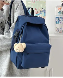 Detail shot of navy blue nylon backpack featuring cute bear plush pendant for casual daily use.