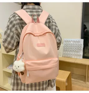 Pink casual school backpack detail view with cute plush cloud pendant and front zipper pocket.