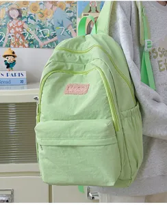 Detail view of light green casual backpack, multi-pocket design, daily student schoolbag.
