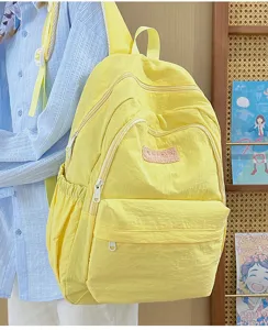 Detail view of the yellow casual canvas backpack, featuring front pocket and zipper structure.