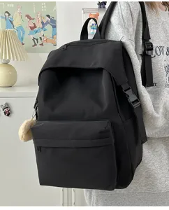 Detailed view of casual black nylon backpack, showcasing side straps and cute plush pendant.