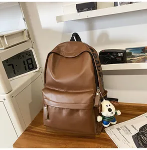 Brown PU leather backpack for women, waterproof school bag with cute dog pendant.