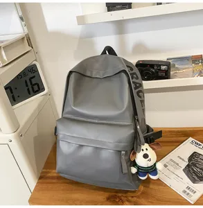 Grey PU leather minimalist waterproof backpack detail view, featuring side letter print.