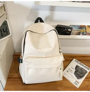 Detail view of the minimalist white PU leather backpack on wooden desk with stylish props.