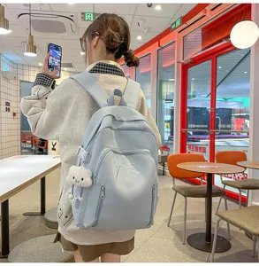Detailed shot of cute light blue student backpack with bow embroidery and cloud pendant in cafe.