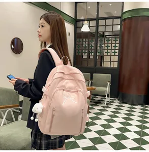 Pink canvas school backpack for teen girls, cute bow design with plush pendant, large capacity.