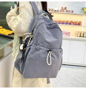 Detail view of the gray nylon backpack showing its large capacity and front drawstring.