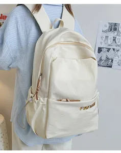 Detail shot of the minimalist casual cream backpack showing side pocket and metal logo accent.