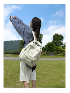Outdoor lifestyle detail shot of a minimalist white canvas backpack worn by model in park.