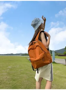 Outdoor detail view of the casual orange backpack worn by model, showing style and design.