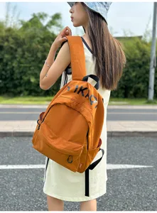 Outdoor lifestyle detail shot showcasing the casual orange backpack design and textured fabric.