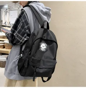 Minimalist black backpack for women, cute bear patch school bag for casual daily use and travel.