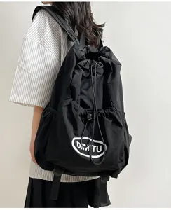 Detail shot of black lightweight drawstring backpack featuring front pocket and adjustable straps.