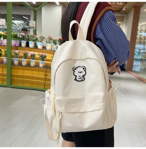 Detailed view of casual canvas backpack with cute bear patch, stylish daily school bag for students.