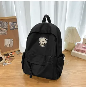 Black canvas school backpack with cute bear patch, minimalist casual daypack for students.