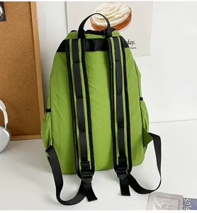 Detailed view of green drawstring backpack with adjustable black shoulder straps on white desk.