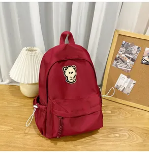 Minimalist red canvas school backpack with cute bear patch, casual student daypack for daily use.