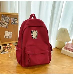 Casual school backpack for students with cute bear patch, stylish daily travel bag in dark red.