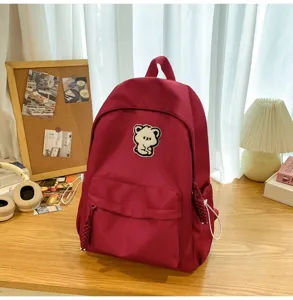 Casual red school backpack for women, cute bear patch detail, retro ins style daily bag.