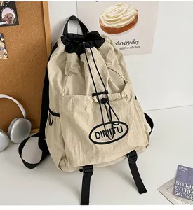 Close-up detail of khaki drawstring backpack featuring front pocket and adjustable straps.
