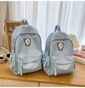 Light blue student backpack detail, minimalist cute bear patch and woven pendant, daily school bag.