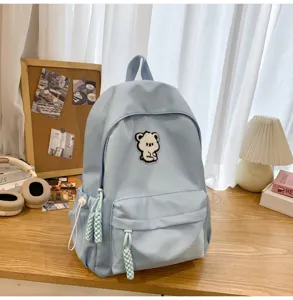 Detailed closeup of light blue student backpack featuring cute embroidered bear patch.