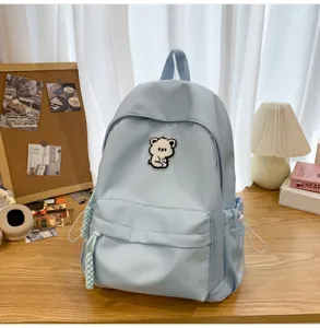 Detail view of light blue backpack with cute bear patch, casual student schoolbag.