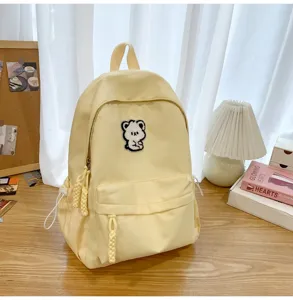 Cute yellow student backpack detail with adorable bear patch, casual cozy desk setup style