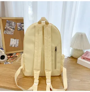 Minimalist canvas school backpack in light yellow, detailed view showing back straps and pocket.