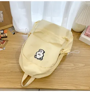 Casual minimalist yellow canvas backpack detail featuring a cute white bear patch.