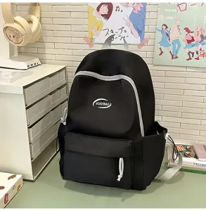 Vista detallada de mochila escolar negra casual con cremallera blanca y diseño de bolsillo.