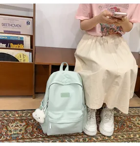 Casual light green school backpack detail view, featuring front pocket and cute plush pendant.