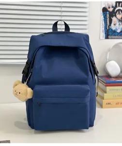 Close-up detail of the blue nylon backpack with cute bear pendant and side pockets.
