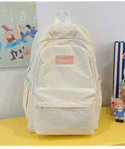 Detail shot of simple minimalist beige backpack featuring cute plush patch, lightweight daily school bag.