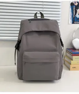 Detail shot of a grey nylon casual backpack on a clean white desk setup with minimalist props.