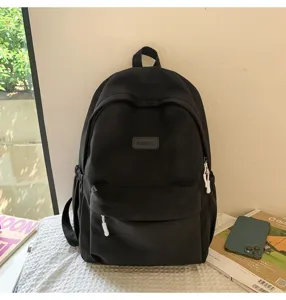 Detailed shot of a black minimalist canvas backpack, showcasing front pocket and smooth zipper.