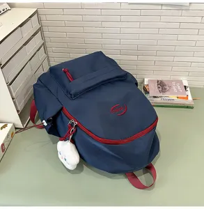 Mochila escolar azul oscuro con cremalleras rojas y lindo colgante de nube blanca.