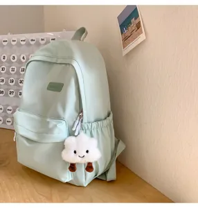 Mint green Japanese style school backpack with cute cloud plush pendant, detail display scene.